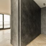 The interior of an empty spacious room with a panoramic window and access to the balcony